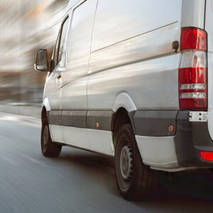 White delivery van driving on urban road.