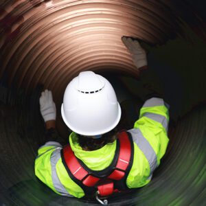 Worker inspecting inside large industrial pipe.