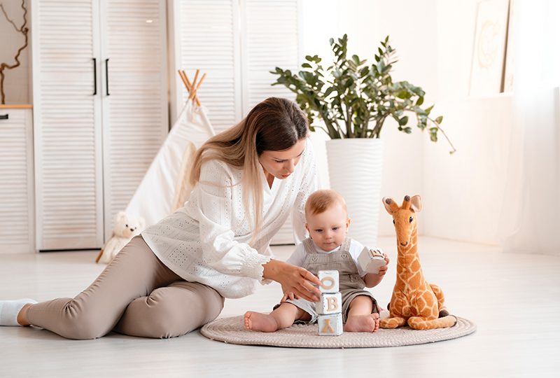 Mother and baby playing with blocks indoors.
