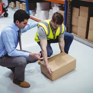 Two men inspecting a package in a warehouse.