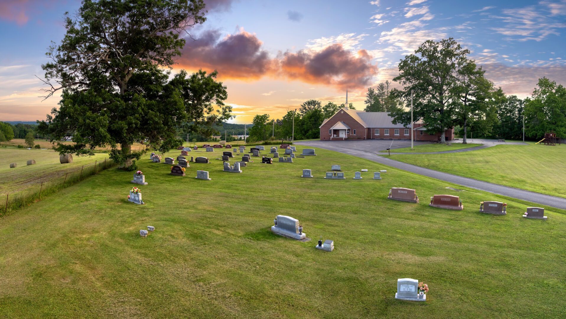 Cemetery graveyard with many tombstones near small church in rural American town. Burial place on green grass. SSUCv3H4sIAAAAAAAACpRTy47bIBTdjzT/ELFuVMBgkv5D1arbURfXholRCFg8pq1G+feCbVIyaqt253sO99zX8evjw26HBgh6RB92ryXKsTYmheghamczjN9tuFdWKt8iL77rcQuAbiMldXReg2nBAeI4WbioDNpkTIGvC4lChJiCCk0vYUoxKh+iG88Z7qrK7KzkGSAVuLgQ58lFF1p01t8jlLymyghRnXJbd3XqDp7WeFeJhcwZmUJflNGnspNNfW0wDYX7qMOojAGrXAqo8mvFP8h9Bn8O7z+lKJ3z/6G5fny9rfyk7PijjHJthvTKKFhX+bQ+RedveZGXZejtESSpXbOEFzeCCW/WBXoGD3d5s9ejtqcGcXFanFGVRpds9KUrRCmtwyHj3AyDKad/zpVUxScIIWfIirfXylZ0l6aUdXEZC62qSOZzlpB0jHQC4473hGNCGUatqyaddZaOao9pNg6kKkVv13nrNyJYzxnrRXVUaz3BBO4JPdJf3L0LBe8E67quTd4MuXICU7ZS1Snl9hedW/iHtgTH/PfKRyHEkWzKdz9YztfyLz8Yoj3NGxSU8dvVqjIilHLCj4duMeOmqUunSIEahAK+Vxzwnsl+2B8IYfteYAmkfz4UwceH608AAAD//wMAP7IhjHIEAAA=